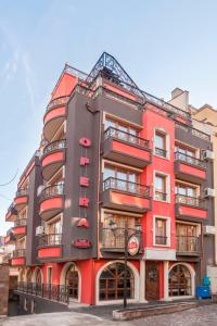 un edificio rojo con balcones en un lateral en Семеен Хотел Опера, en Burgas