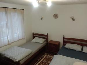 zwei Einzelbetten in einem Zimmer mit Fenster in der Unterkunft Casa din Săcădat-Szakadáti Vendégház in Sovata