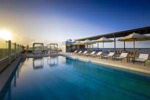 カンクンにあるResidence Inn by Marriott Cancun Hotel Zoneの建物内のスイミングプール(椅子、パラソル付)