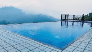 a swimming pool with blue water and mountains in the background at Silver cascade in Devikolam