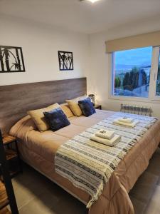a large bed in a room with a large window at COMARCA SUR Apartamentos in Ushuaia