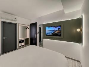 a bedroom with a white bed and a flat screen tv at The Concept Hotel HCMC- Premium in Ho Chi Minh City