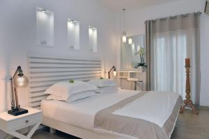 a white bedroom with a large bed with white pillows at Apollon Boutique Hotel in Parikia