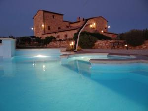 a swimming pool in front of a house at night at Agriturismo Il Macchione in Pienza