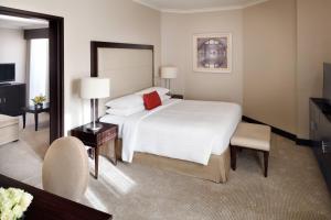 a bedroom with a large white bed and a television at Riyadh Marriott Hotel in Riyadh