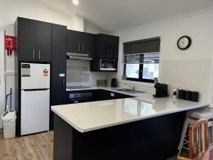a kitchen with black cabinets and a white refrigerator at Sea Lake Holiday Cabin in Sea Lake