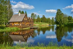 eine Blockhütte neben einem Fluss mit Bäumen in der Unterkunft Kivi Talu Country Hotel in Otepää