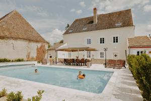 two people in a swimming pool in front of a house at Gîte de charme - 4 étoiles - 20 min de Beaune - Maison Saunières in Saunières
