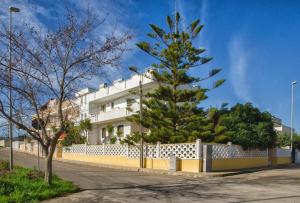 a tree in front of a white building at Magia del Salento in Torre San Giovanni Ugento