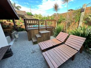 a patio with a wooden bench and a fence at Casa privativa com piscina na Praia da Ferrugem duas quadras mar REF 100 in Garopaba