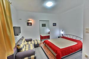 a bedroom with a bed and a couch and a tv at Guesthouse Sermageova in Zagreb