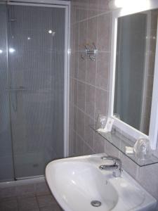 uma casa de banho com um lavatório e um chuveiro com um espelho. em Auberge De La Luzerne em Bernières-sur-Mer