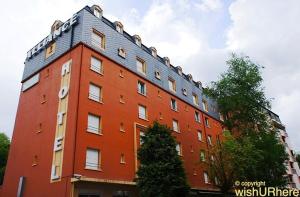 um grande edifício vermelho com um telhado cinzento em Hôtel Alliance em Lourdes