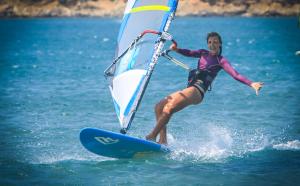 a woman on a board with a sail on the water at Prasonisi Club in Kattavía