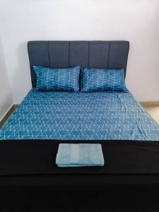 a bed with a blue comforter and two blue pillows at SK Sweet Homestay SP Kedah in Sungai Petani