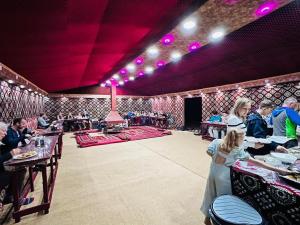 a group of people sitting at tables in a restaurant at Wadi Rum Story Camp in Wadi Rum