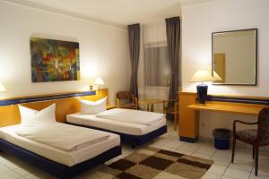 a hotel room with two beds and a desk at Hotel Rahlstedter Hof in Hamburg