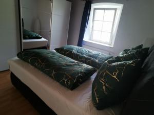 a bed with two pillows on it with a window at Idyllische Ferienwohnung nahe Nürburgring in Walsdorf