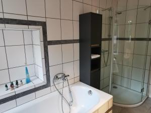 a bathroom with a tub and a shower and a sink at Idyllische Ferienwohnung nahe Nürburgring in Walsdorf +8 photos
