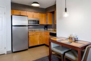 a kitchen with a white refrigerator and a table at Residence Inn Denver North/Westminster in Westminster