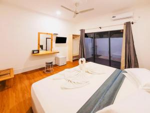 Un dormitorio con una cama blanca con una ventana grande. en Hi Heaven Thoddoo, en Thoddoo