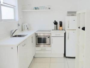 a white kitchen with a sink and a microwave at Appartement Chandon 4 pers in Willemstad
