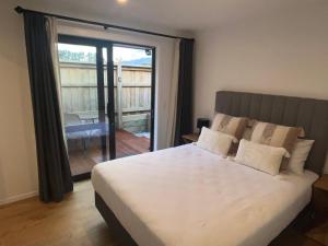 una camera da letto con un grande letto bianco e un balcone di Studio in Glenorchy a Glenorchy
