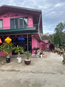 ein rosafarbenes Gebäude mit Topfpflanzen davor in der Unterkunft Thương Thương Đà Lạt 2 in Xuan An
