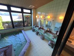 a bathroom with a large tub and a large mirror at 湖上館パムコ in Wakasa