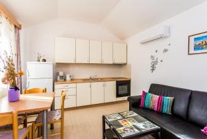 eine Küche und ein Wohnzimmer mit einem Sofa und einem Tisch in der Unterkunft Lavanda 3 in Njivice