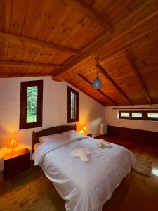 エプタロフォスにあるAnemoria Chalets-Castalia Chaletの木製の天井の客室で、ベッドルーム1室(大きな白いベッド1台付)
