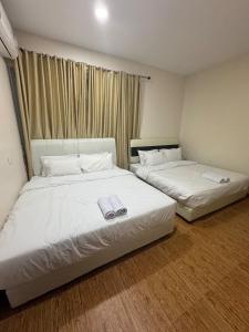 two beds in a room with white sheets at Monde Residence Block K number 17 in Bagam