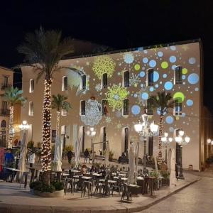 a building with tables and palm trees in front of it at A viuzza in Cefalù