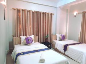 two beds in a room with purple pillows on them at Sok San Boutique and Spa in Siem Reap +6 photos