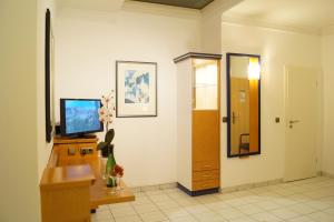un couloir avec une télévision, un bureau et une porte dans l'établissement Hotel Rahlstedter Hof, à Hambourg