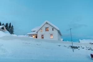 特罗姆瑟Explore Tromsø Villa的黄昏时分，雪中的一栋白色房子