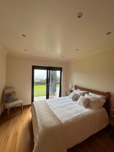 a bedroom with a large white bed and a window at Deluxe House in Angra do Heroísmo