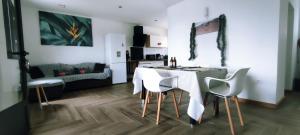 a dining room with a table and white chairs at Villa la fournaise in Le Tampon