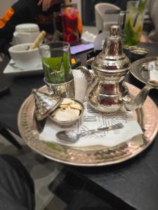 a table with a plate with a teapot and a tea kettle at La Cascade Ḩammām al Ghazzāz in Kelibia