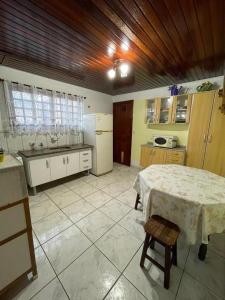 a kitchen with a table and a refrigerator and a table and chairs at Recanto da Araucária 2 in Campos do Jordão
