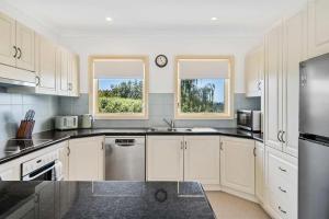 a kitchen with white cabinets and stainless steel appliances at Lizzy's Hideaway, Close to City in West Hobart