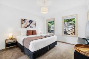 a bedroom with a large bed and two windows at Lizzy's Hideaway, Close to City in West Hobart