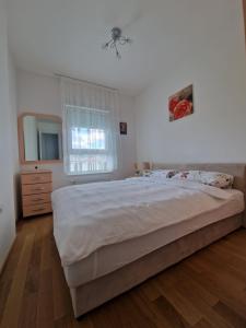 a bedroom with a bed and a dresser and a window at Apartmani Stan na dan 34 in Banja Luka