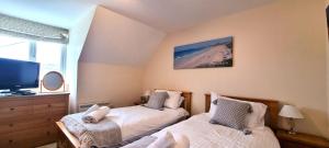 ein Schlafzimmer mit zwei Betten und einem Fernseher an der Wand in der Unterkunft 15 Penhale, Perranporth in Perranporth