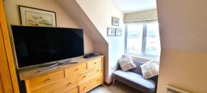 ein Wohnzimmer mit einem Flachbild-TV und einem Stuhl in der Unterkunft 15 Penhale, Perranporth in Perranporth