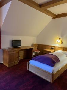 a bedroom with a bed and a tv on a desk at Hotel Gasthof Zum Ochsen in Furtwangen