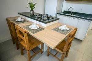 a kitchen with a wooden table with chairs and a stove at Loft Novo Campeche in Florianópolis