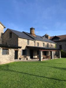 a large stone building with a grass yard at Casa Rural Aracanciás in Borrastre
