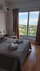 a bedroom with a bed with towels and a large window at Tango 4C in Victoria