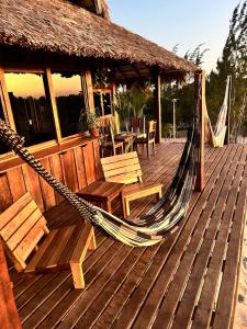a wooden deck with a hammock and tables and chairs at Sunset Valley Bungalow in Camocim +21 photos